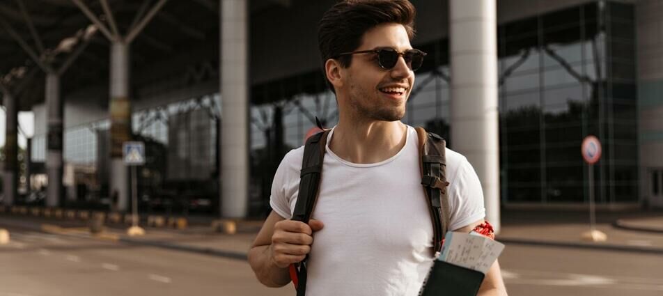 Homem saindo do aeroporto com passagens na mão